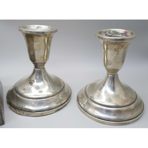 7366 - A silver cigarette box, 517g with liner, and a pair of candlesticks marked 'Sterling, Weighted & Rei... 