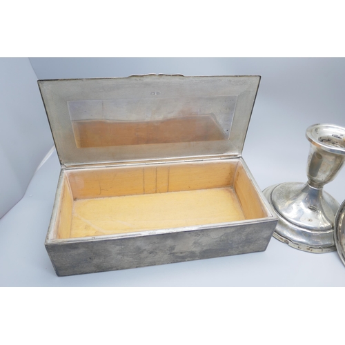 7366 - A silver cigarette box, 517g with liner, and a pair of candlesticks marked 'Sterling, Weighted & Rei... 