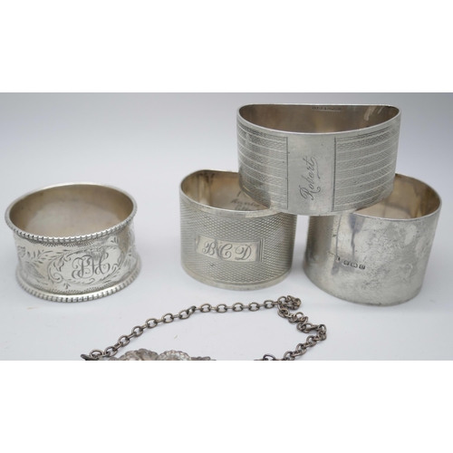 7376 - Four silver napkin rings, a silver ashtray and a silver port label, 224g