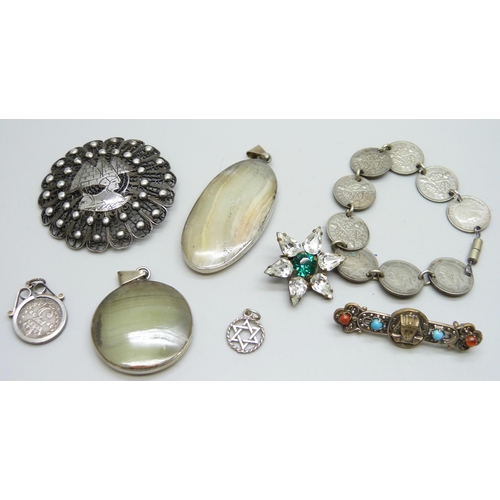 7070 - Two silver mounted stone pendants, two Egypt detail brooches, a coin bracelet, etc.