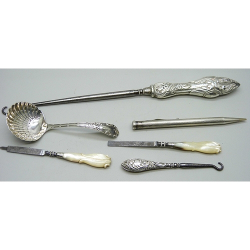 7151 - A silver sifter spoon, two silver mounted button hooks, a rolled silver pen, etc. (tweezers a/f)