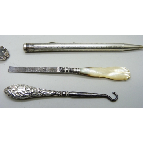 7151 - A silver sifter spoon, two silver mounted button hooks, a rolled silver pen, etc. (tweezers a/f)