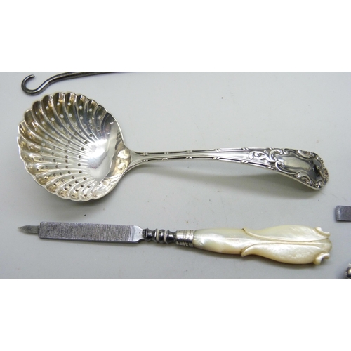 7151 - A silver sifter spoon, two silver mounted button hooks, a rolled silver pen, etc. (tweezers a/f)