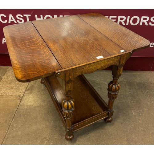 145 - A 17th Century style carved oak drop leaf trolley