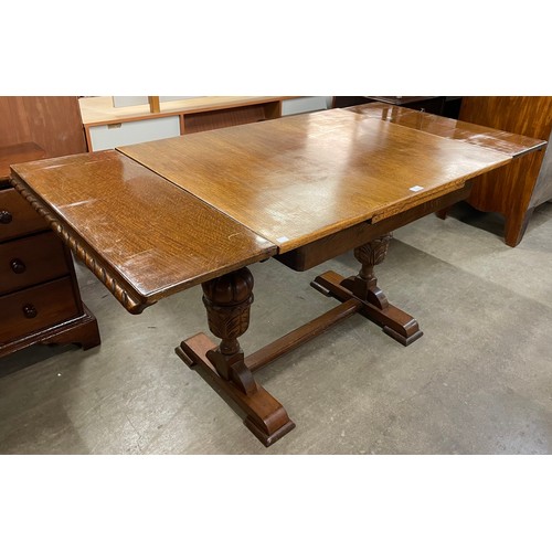 117 - An early 20th Century carved oak draw-leaf dining table