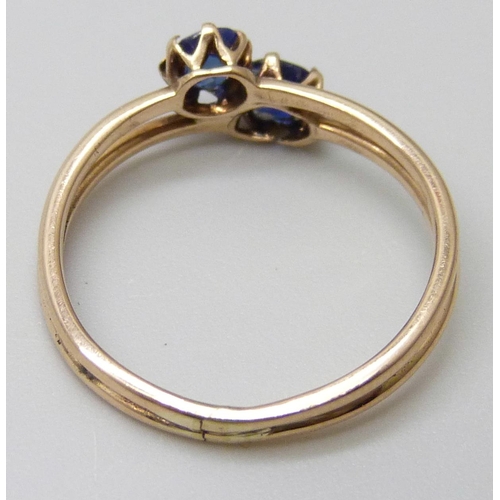 7037 - A 14k gold two stone sapphire crossover ring, 1.7g, K