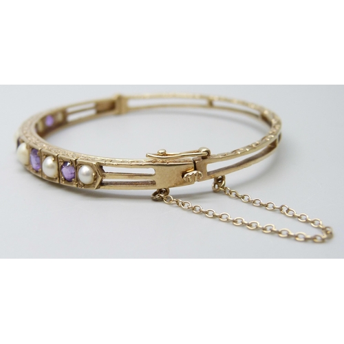 7038 - A 9ct gold, amethyst and pearl bangle, 11.8g, 5.9 x 5.1cm