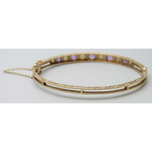 7038 - A 9ct gold, amethyst and pearl bangle, 11.8g, 5.9 x 5.1cm