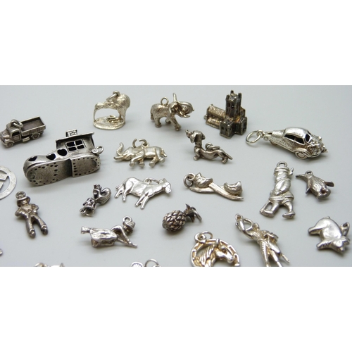 7055 - A collection of silver and white metal bracelet charms including a hallmarked shoe charm, opening to... 