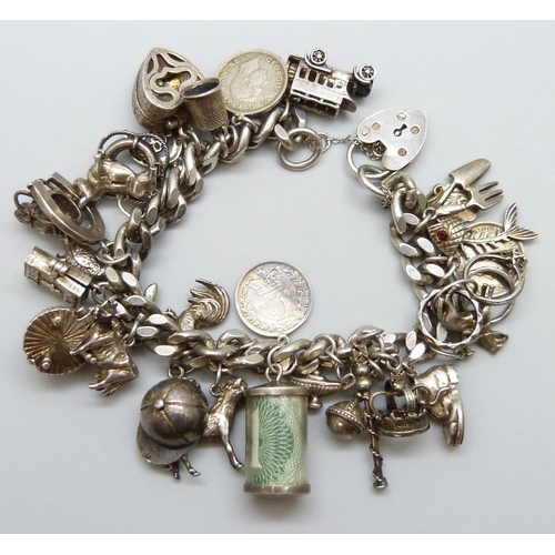 7065 - A silver charm bracelet with 28 silver and white metal charms, the padlock fastener Birmingham 1975,... 