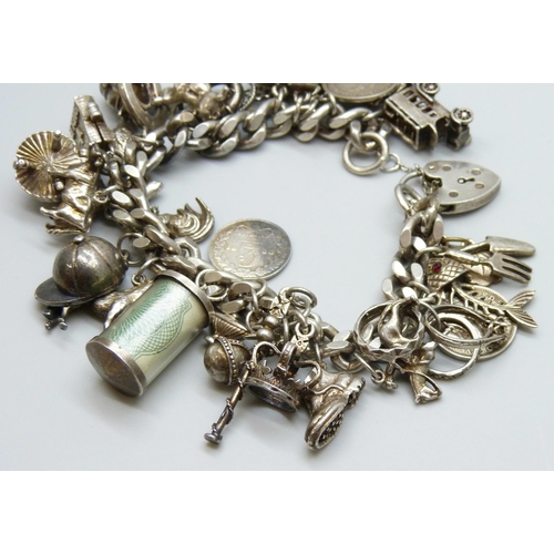 7065 - A silver charm bracelet with 28 silver and white metal charms, the padlock fastener Birmingham 1975,... 