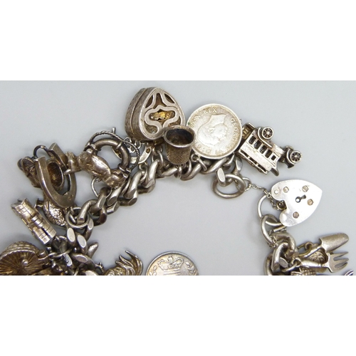 7065 - A silver charm bracelet with 28 silver and white metal charms, the padlock fastener Birmingham 1975,... 