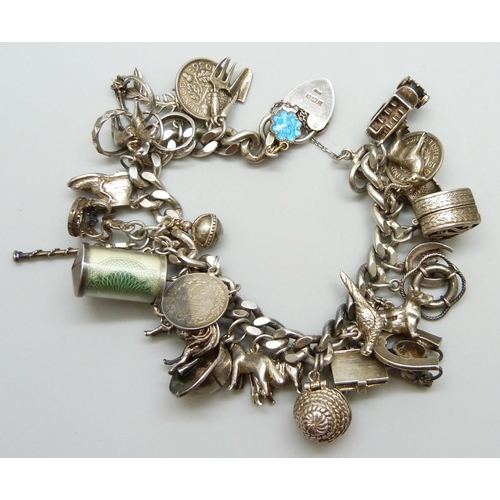 7065 - A silver charm bracelet with 28 silver and white metal charms, the padlock fastener Birmingham 1975,... 