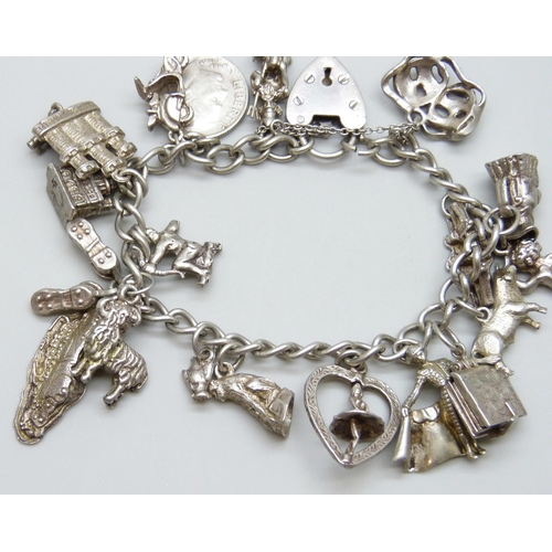 7071 - A silver charm bracelet with 18 silver and white metal charms, 59g