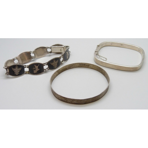 7072 - Two silver bangles and a Siam silver niello bracelet, 52g