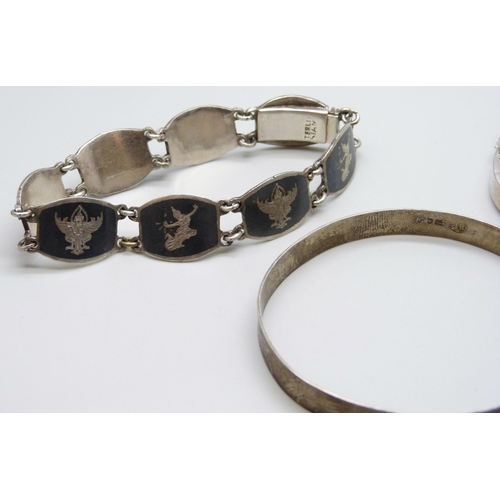 7072 - Two silver bangles and a Siam silver niello bracelet, 52g