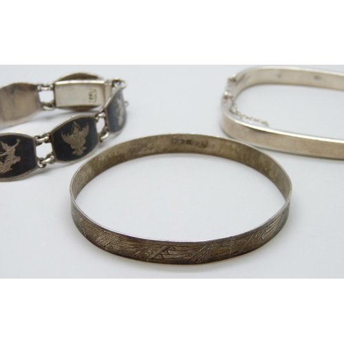 7072 - Two silver bangles and a Siam silver niello bracelet, 52g