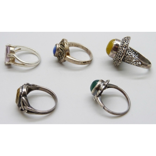 7074 - Four silver rings and a white metal purple stone ring, 26g