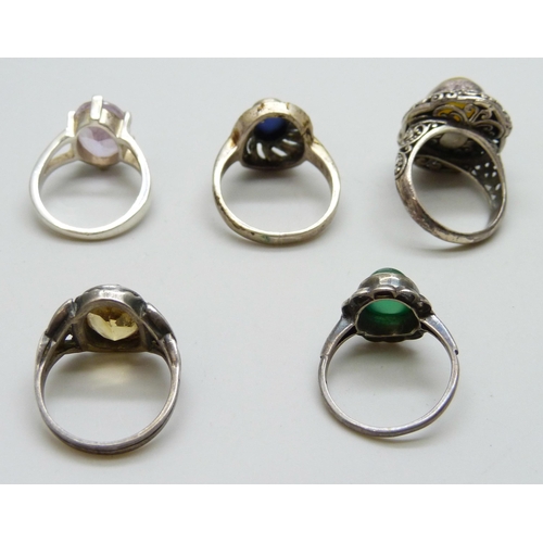 7074 - Four silver rings and a white metal purple stone ring, 26g