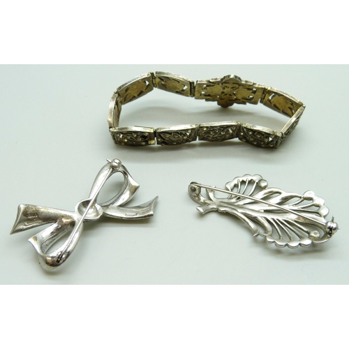 7078 - A gilt white metal bracelet set with paste stones, a silver bow brooch and a white metal brooch, 42g