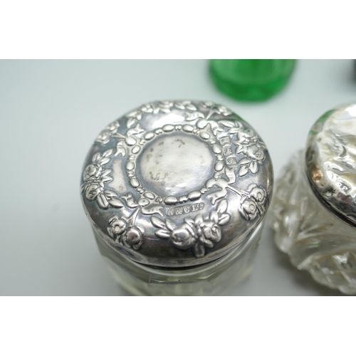 7258 - A white metal mounted double scent bottle, a green glass scent bottle, together with two silver topp... 