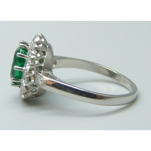 7039 - A platinum ring set with a central emerald and diamond halo and shoulders, 5.2g, N