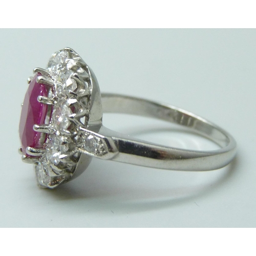 7048 - A platinum ring set with a central ruby and diamond surround and shoulders, 9mm x 6mm ruby, 6.3g, N