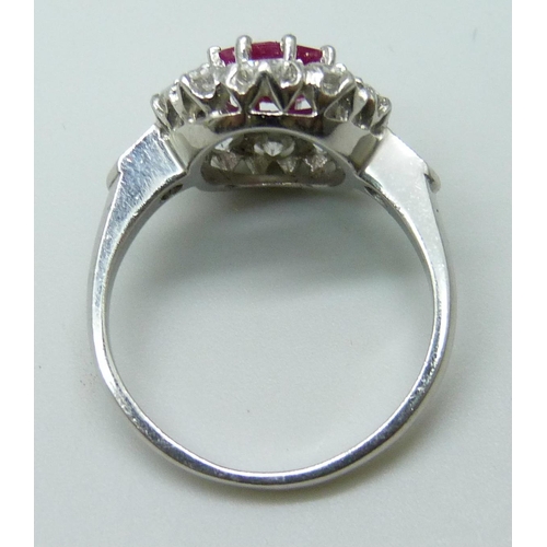 7048 - A platinum ring set with a central ruby and diamond surround and shoulders, 9mm x 6mm ruby, 6.3g, N