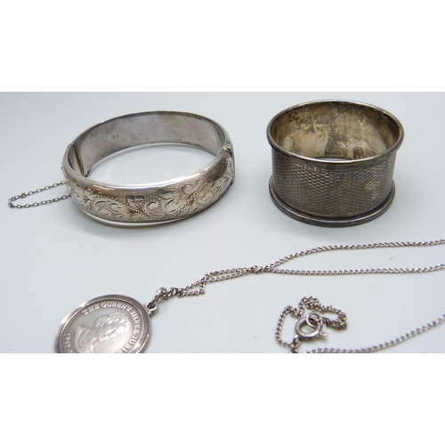 7098 - A collection of silver - a bangle, ingot, drilled coin, pendant on a white metal chain, and a napkin... 