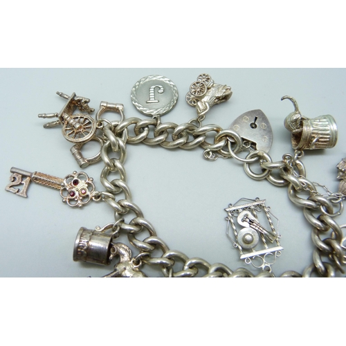 7099 - A silver curb link charm bracelet with 19 silver and white metal charms, and a white metal articulat... 