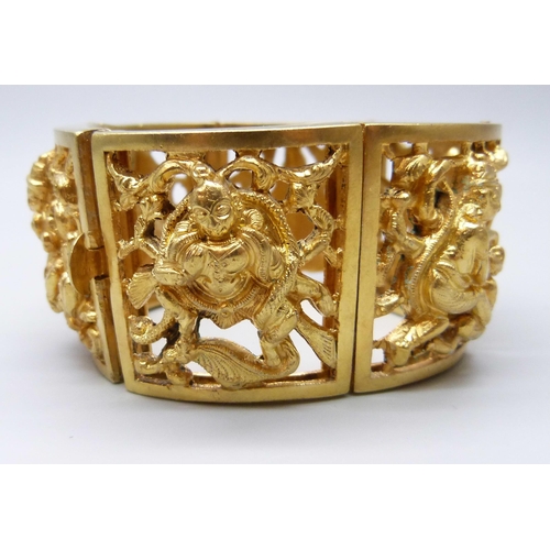 7112 - An Eastern gilt metal fretwork panel bangle, 104g,  3.5cm wide