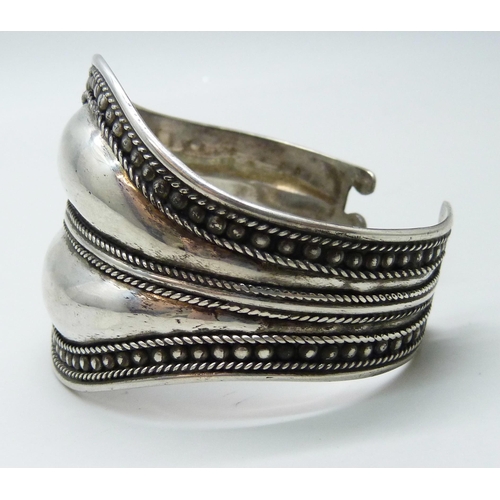 7113 - A handmade white metal statement bangle, possibly South American, indistinctly stamped 925, 40g