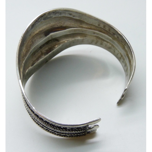 7113 - A handmade white metal statement bangle, possibly South American, indistinctly stamped 925, 40g