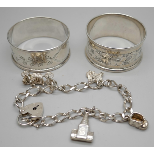 7254 - Two silver napkin rings and a silver bracelet with white metal charms, 36g total