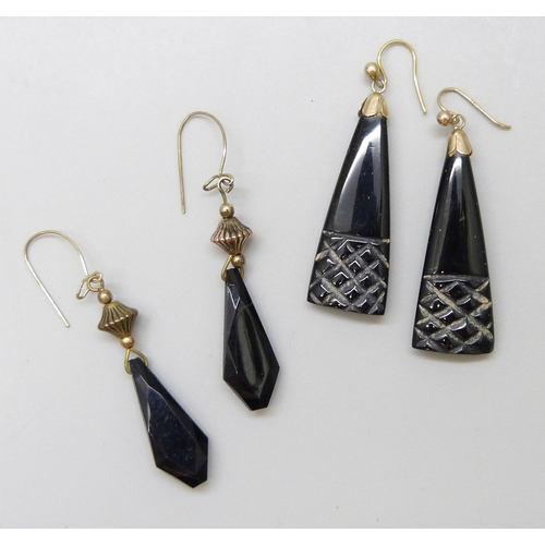 7070 - A pair of carved jet earrings with yellow metal hooks, and another pair of plastic earrings with gil... 