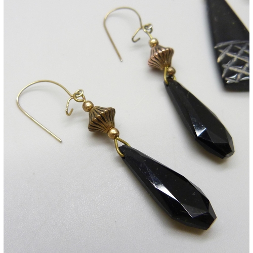 7070 - A pair of carved jet earrings with yellow metal hooks, and another pair of plastic earrings with gil... 