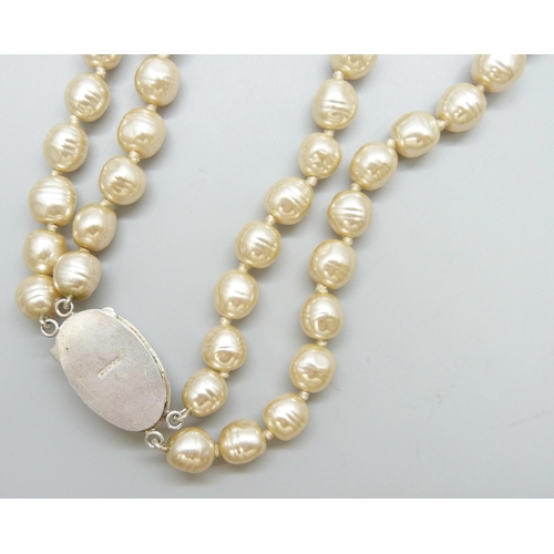 7088 - A double string of pearls set with a large silver clasp, 145g, pearls approximately 1cm