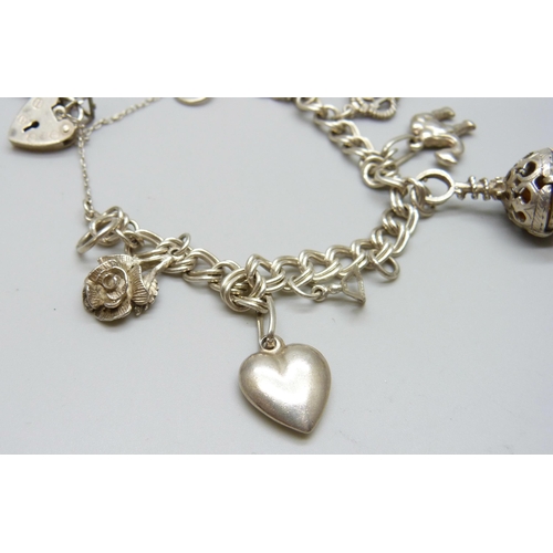 7110 - A silver charm bracelet with white metal charms, 36g