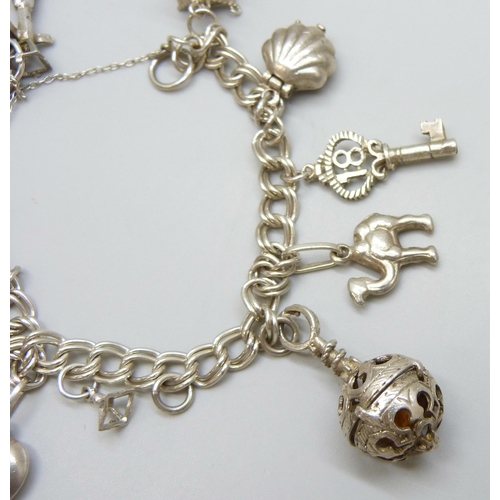 7110 - A silver charm bracelet with white metal charms, 36g