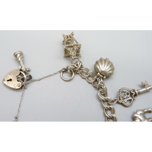 7110 - A silver charm bracelet with white metal charms, 36g