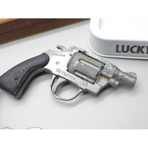 2070 - A Lone Star toy cap gun, a lighter cigarette case combination, a cigarette box, a Lucky Strike ashtr... 