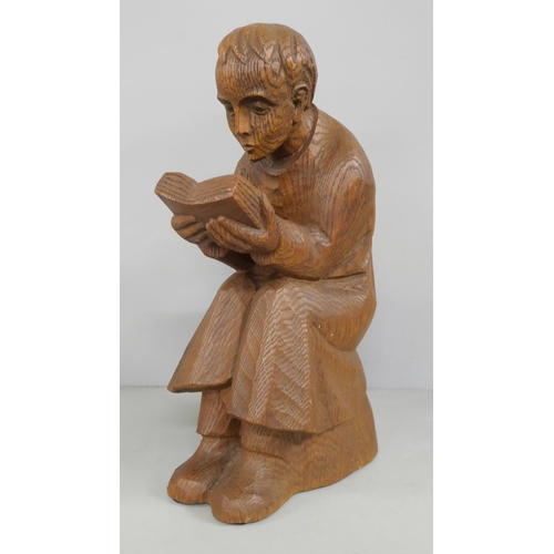 2196 - A mid 20th century oak carving of a young monk reading a book, a carved wooden model of a Germanic G... 