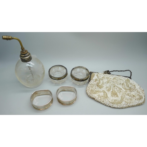 7250 - Two silver napkin rings, 22g, two silver rimmed salts, an atomiser with silver collar, and a beadwor... 