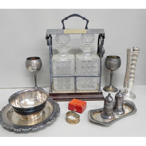 2106 - A tantalus with plated stand, goblets, vase and a silver napkin ring