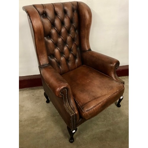 105 - A chestnut brown leather wingback armchair