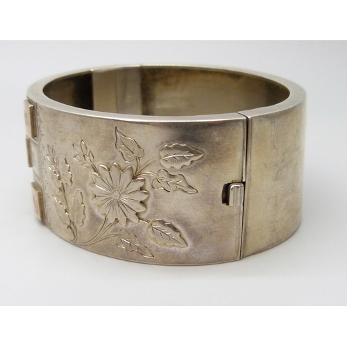 7102 - A Victorian white metal bangle with applied gold decoration, 36g, 4.7 x 5.7cm, 2.5cm wide