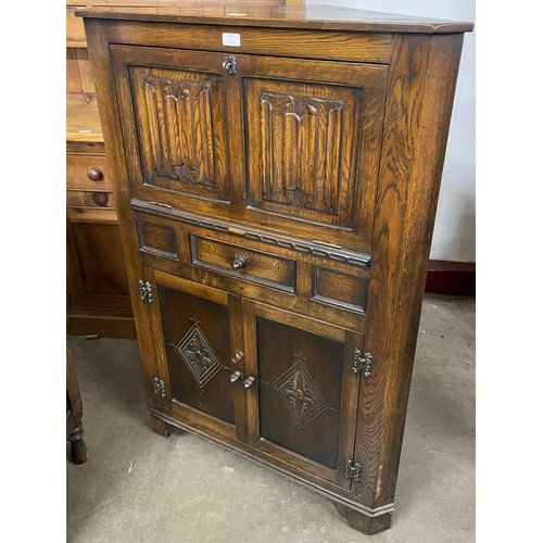 254 - An early 20th Century carved oak linenfold splay front corner cupboard