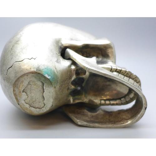 2026 - A novelty plated skull paperweight with hinge jaw, height 9cm