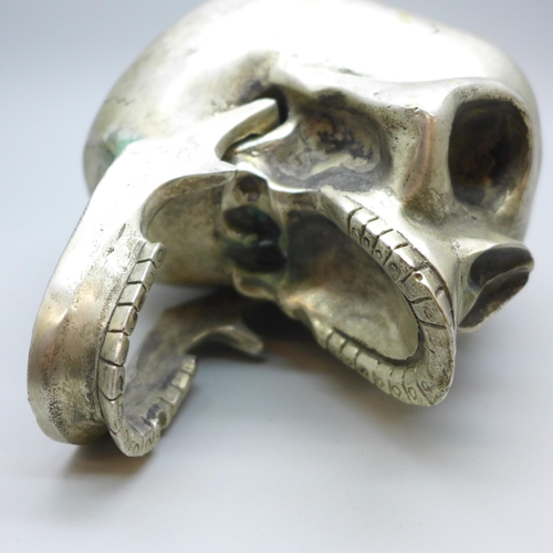 2026 - A novelty plated skull paperweight with hinge jaw, height 9cm