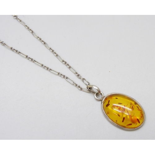 7082 - A silver amber set ring, a silver mounted amber pendant on chain, and a white metal amber ring